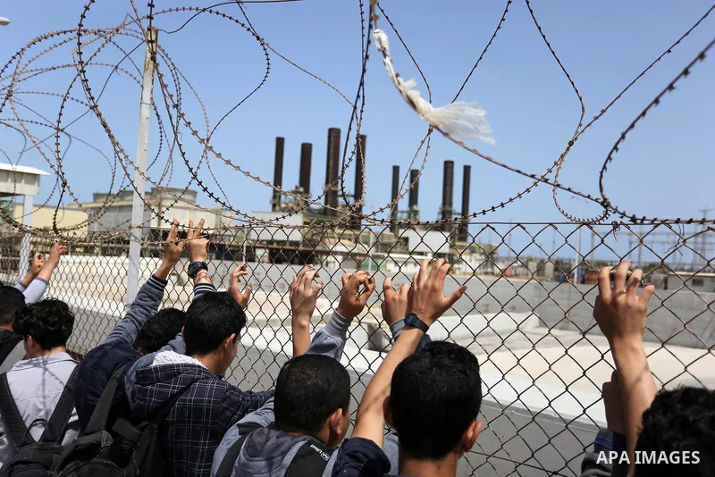 Palestinian school boys stand by a fence during a protest calling for an end to the power crisis, outside the power plant in the central Gaza Strip April 23, 2017. Photo by Ashraf Amra