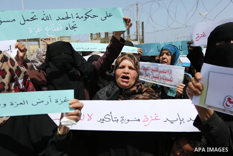 Palestinian women hold banners during a protest calling for an end to the power crisis, outside the power plant in the central Gaza Strip April 23, 2017. Photo by Ashraf Amra