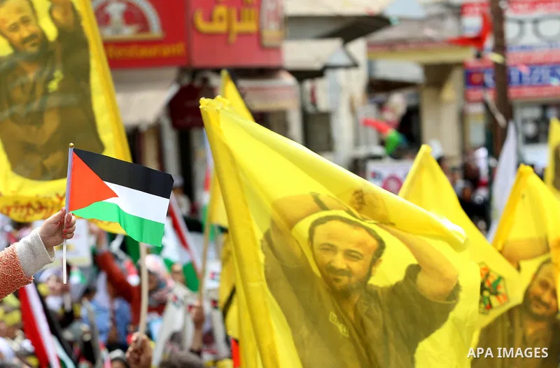 Palestinian protesters wave flags bearing the portrait of prominent prisoner and popular leader Marwan Barghouti during a demonstration in solidarity with Palestinian prisoners on hunger strike in Israeli jails, in the W...