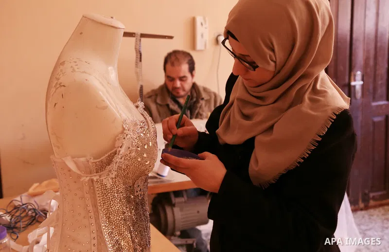 Manar Tafesh, 30, a Palestinian fashion designer works on knitting wedding dresses at her house with her husband to help him after he lost his work as tailor in the Palestinian territory occupied, in Gaza city on Feb. 14...