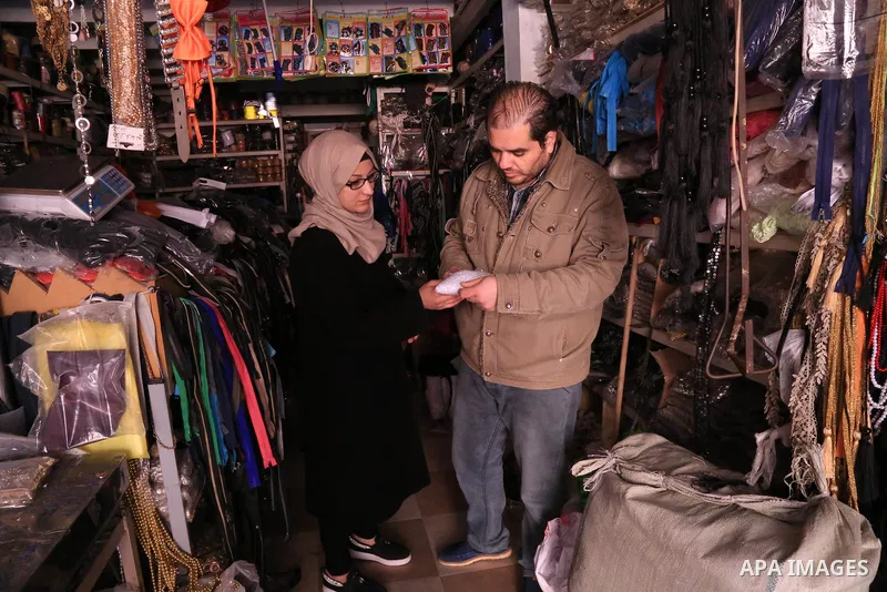 Manar Tafesh, 30, a Palestinian fashion designer buys sewing kit as she works on knitting wedding dresses at her house with her husband to help him after he lost his work as tailor in the Palestinian territory occupied,...