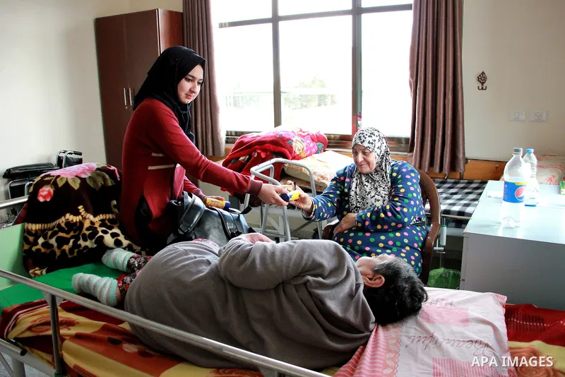 A Palestinian female volunteer presents gift for an elderly Palestinian woman at El Wafa elderly nursing home, in Gaza city on Feb. 12, 2017. El Wafa elderly nursing home was established in 1980 as one of programs of Al-...