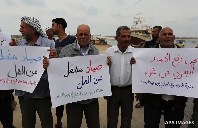 Palestinian fishermen hold banners during a protest demanding end an Israeli blockade of the Gaza Strip, in Gaza city on April 26, 2017. Photo by Ashraf Amra