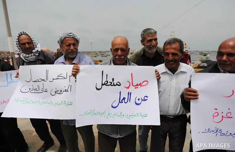 Palestinian fishermen hold banners during a protest demanding end an Israeli blockade of the Gaza Strip, in Gaza city on April 26, 2017. Photo by Ashraf Amra