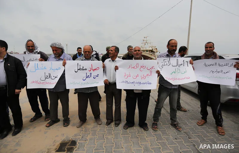 Palestinian fishermen hold banners during a protest demanding end an Israeli blockade of the Gaza Strip, in Gaza city on April 26, 2017. Photo by Ashraf Amra