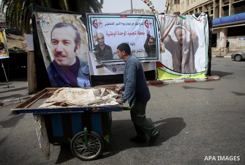 A Palestinian vendor walks past a a protest tent in support of Palestinian prisoners on hunger strike in Israeli jails, in the West Bank city of Nablus on April 26, 2017. Photo by Ayman Ameen