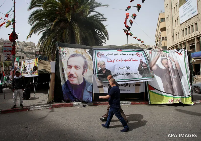 Palestinians walk past a a protest tent in support of Palestinian prisoners on hunger strike in Israeli jails, in the West Bank city of Nablus on April 26, 2017. Photo by Ayman Ameen