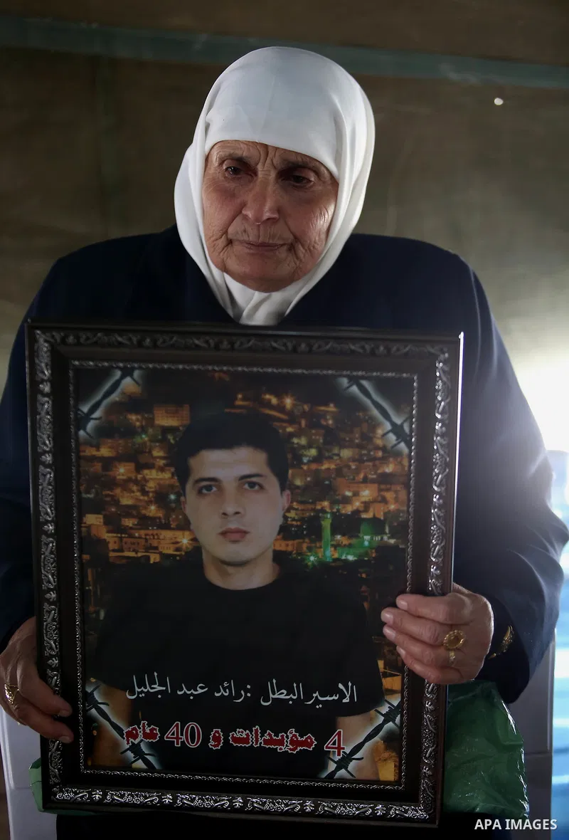 A Palestinian woman holds a picture of her son who held in Israeli jails at a protest tent in support of Palestinian prisoners on hunger strike in Israeli jails, in the West Bank city of Nablus on April 26, 2017. Photo b...