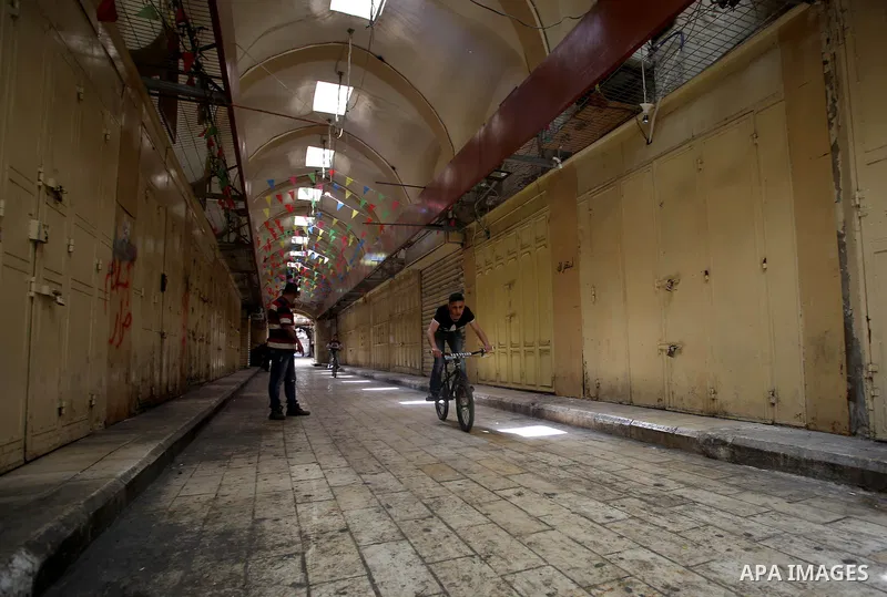 A Palestinian boy rides a bicycle past closed shops during a general strike in support of Palestinian prisoners on hunger strike in Israeli jails, in the old market of the West Bank city of Nablus April 27, 2017. Photo b...