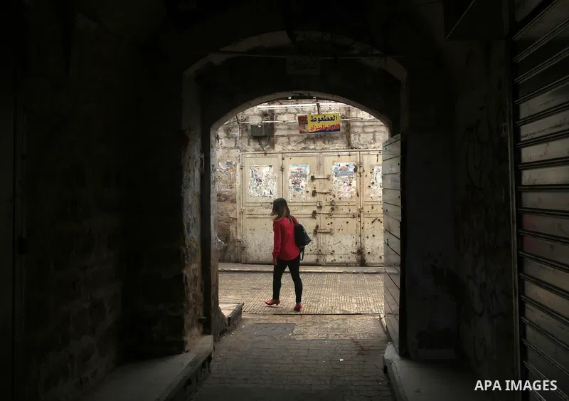 A Palestinian woman walks past closed shops during a general strike in support of Palestinian prisoners on hunger strike in Israeli jails, in the old market of the West Bank city of Nablus April 27, 2017. Photo by Ayman...