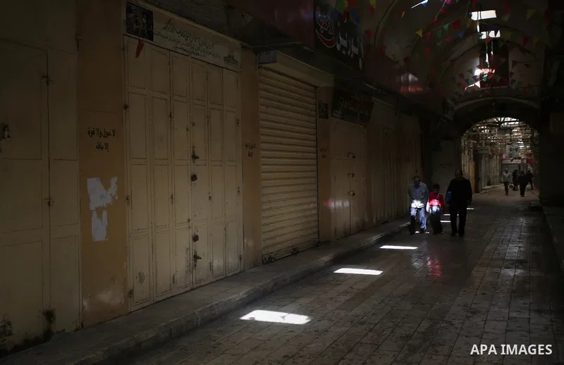 Palestinians walk past closed shops during a general strike in support of Palestinian prisoners on hunger strike in Israeli jails, in the old market of the West Bank city of Nablus April 27, 2017. Photo by Ayman Ameen