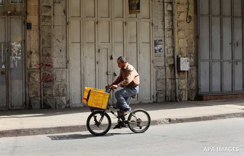 A Palestinian man rides a bicycle past closed shops during a general strike in support of Palestinian prisoners on hunger strike in Israeli jails, in the old market of the West Bank city of Nablus April 27, 2017. Photo b...