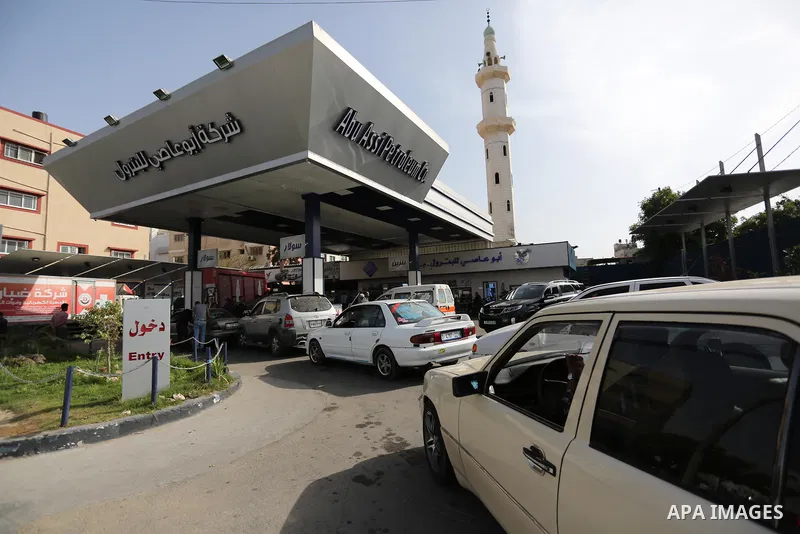 Palestinians wait to fill containers with fuel at a petrol station in Khan Younis in the southern Gaza Strip April 27, 2017. Photo by Ashraf Amra