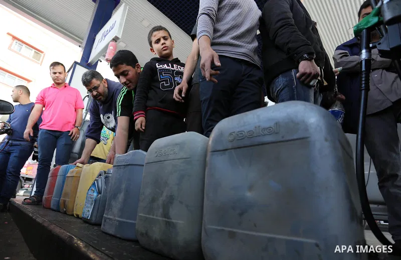 Palestinians wait to fill containers with fuel at a petrol station in Khan Younis in the southern Gaza Strip April 27, 2017. Photo by Ashraf Amra
