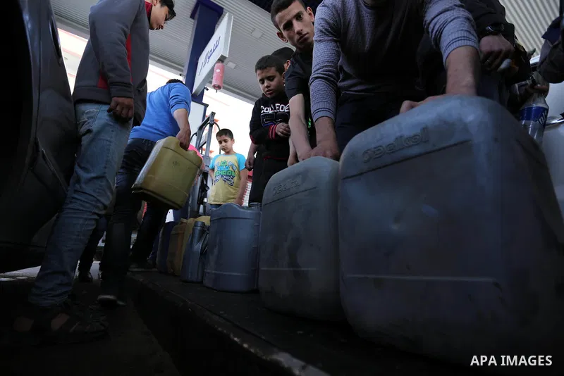 Palestinians wait to fill containers with fuel at a petrol station in Khan Younis in the southern Gaza Strip April 27, 2017. Photo by Ashraf Amra