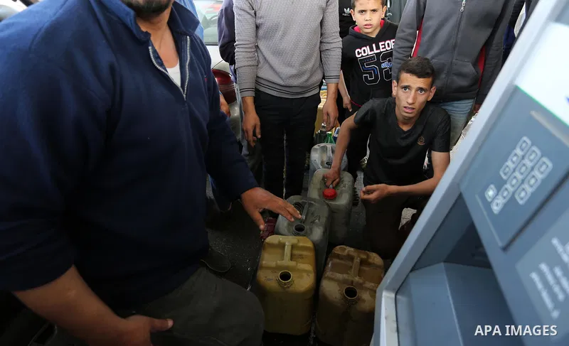 Palestinians wait to fill containers with fuel at a petrol station in Khan Younis in the southern Gaza Strip April 27, 2017. Photo by Ashraf Amra