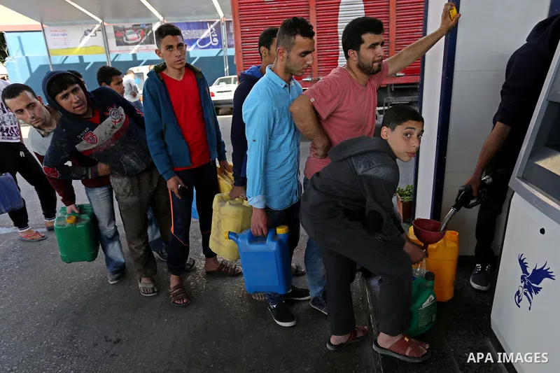 Palestinians wait to fill containers with fuel at a petrol station in Khan Younis in the southern Gaza Strip April 27, 2017. Photo by Ashraf Amra