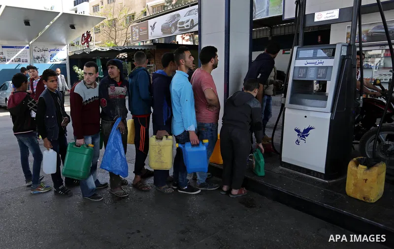 Palestinians wait to fill containers with fuel at a petrol station in Khan Younis in the southern Gaza Strip April 27, 2017. Photo by Ashraf Amra