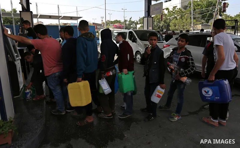 Palestinians wait to fill containers with fuel at a petrol station in Khan Younis in the southern Gaza Strip April 27, 2017. Photo by Ashraf Amra