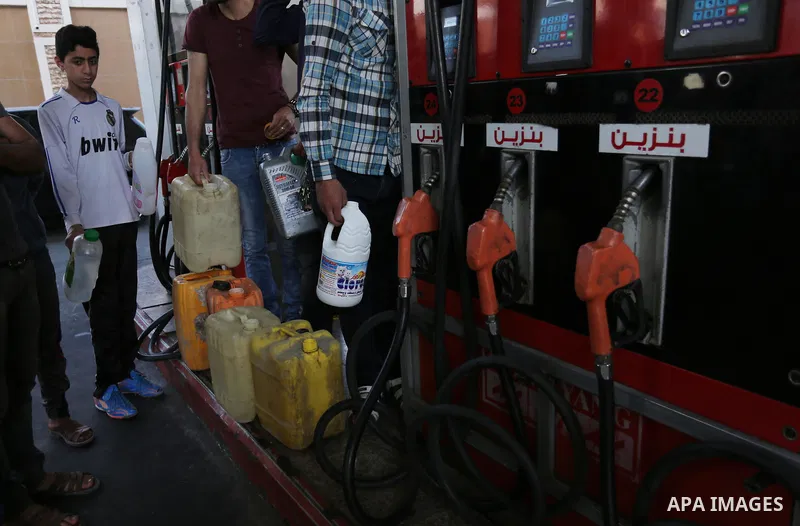 Palestinians wait to fill containers with fuel at a petrol station in Khan Younis in the southern Gaza Strip April 27, 2017. Photo by Ashraf Amra