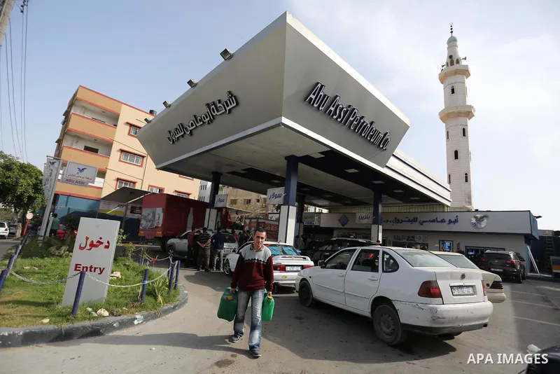 Palestinians wait to fill containers with fuel at a petrol station in Khan Younis in the southern Gaza Strip April 27, 2017. Photo by Ashraf Amra