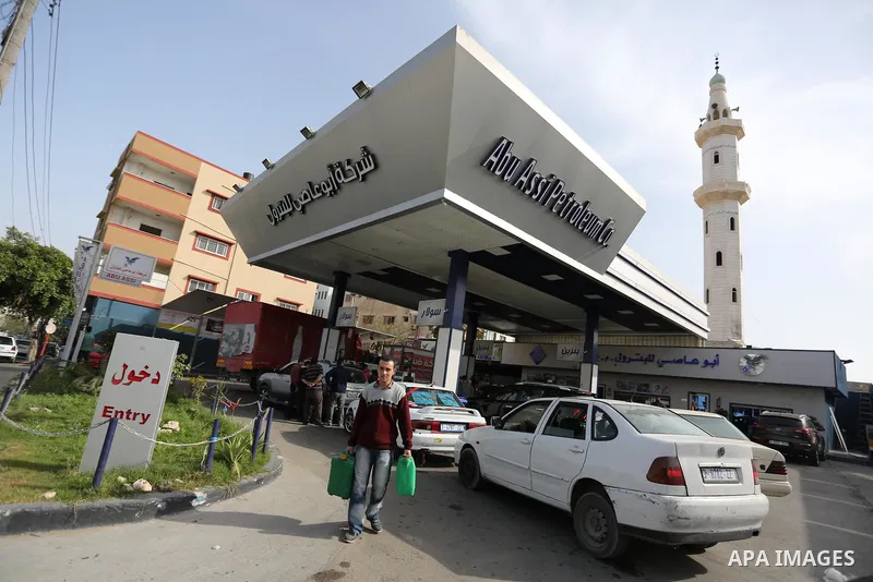 Palestinians wait to fill containers with fuel at a petrol station in Khan Younis in the southern Gaza Strip April 27, 2017. Photo by Ashraf Amra