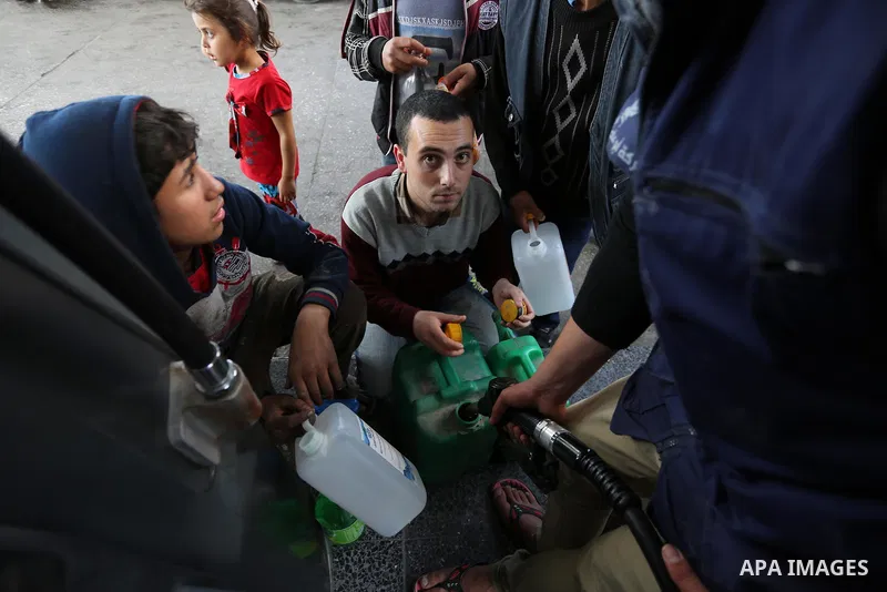 Palestinians wait to fill containers with fuel at a petrol station in Khan Younis in the southern Gaza Strip April 27, 2017. Photo by Ashraf Amra