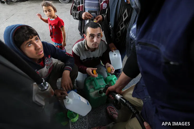Palestinians wait to fill containers with fuel at a petrol station in Khan Younis in the southern Gaza Strip April 27, 2017. Photo by Ashraf Amra