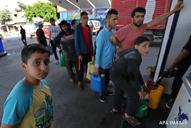 Palestinians wait to fill containers with fuel at a petrol station in Khan Younis in the southern Gaza Strip April 27, 2017. Photo by Ashraf Amra