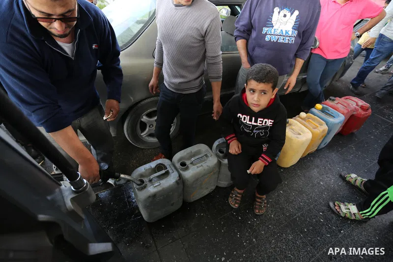Palestinians wait to fill containers with fuel at a petrol station in Khan Younis in the southern Gaza Strip April 27, 2017. Photo by Ashraf Amra