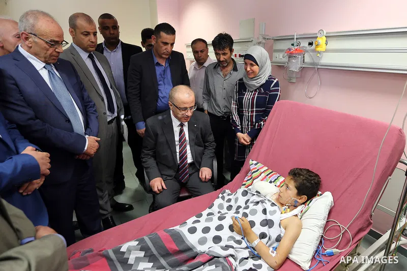 Palestinian Prime Minister Rami Hamdallah visits a nine-year-old Palestinian boy Waqas al-Saifi who lost his arm on Tuesday after being attacked by a bear in the Qalqiliya Zoo, at Najah hospital in the West Bank city of...