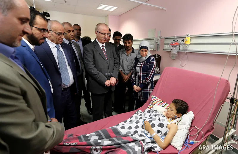 Palestinian Prime Minister Rami Hamdallah visits a nine-year-old Palestinian boy Waqas al-Saifi who lost his arm on Tuesday after being attacked by a bear in the Qalqiliya Zoo, at Najah hospital in the West Bank city of...