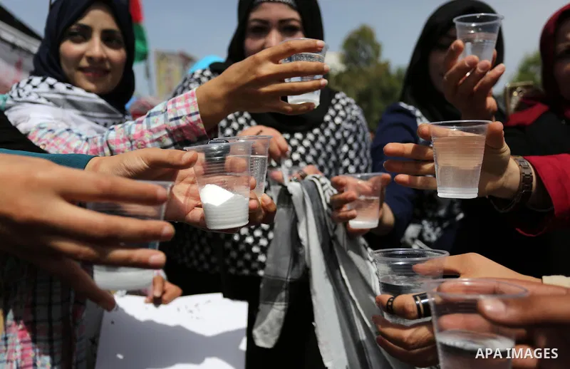 Palestinians drink water and salt during a protest to show solidarity with Palestinian prisoners on hunger strike in Israeli jails, in Gaza city on April 30, 2017. Photo by Ashraf Amra