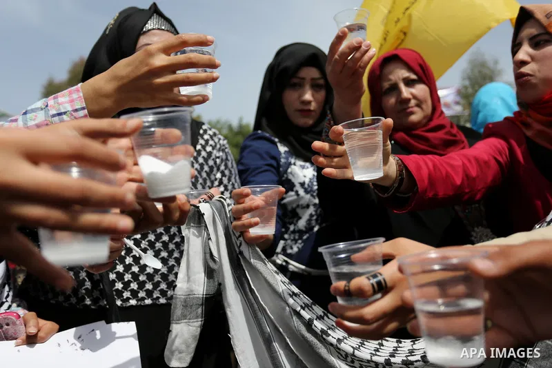 Palestinians drink water and salt during a protest to show solidarity with Palestinian prisoners on hunger strike in Israeli jails, in Gaza city on April 30, 2017. Photo by Ashraf Amra