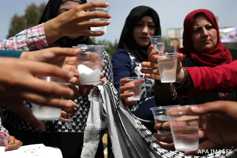 Palestinians drink water and salt during a protest to show solidarity with Palestinian prisoners on hunger strike in Israeli jails, in Gaza city on April 30, 2017. Photo by Ashraf Amra