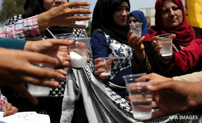 Palestinians drink water and salt during a protest to show solidarity with Palestinian prisoners on hunger strike in Israeli jails, in Gaza city on April 30, 2017. Photo by Ashraf Amra