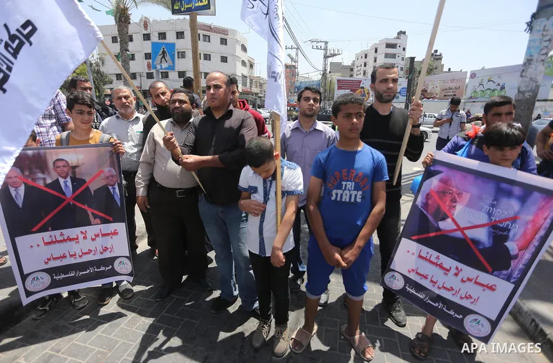 Palestinians hold a poster depicting Palestinian President Mahmoud Abbas during a protest against the blockade, in Gaza city, on May 4, 2017. Photo by Mohammed Asad