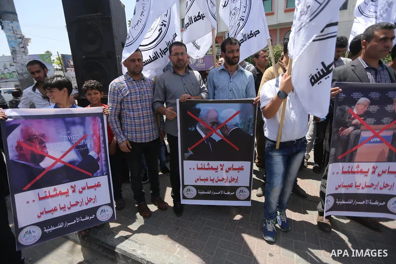 Palestinians hold a poster depicting Palestinian President Mahmoud Abbas during a protest against the blockade, in Gaza city, on May 4, 2017. Photo by Mohammed Asad