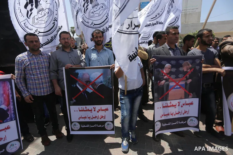 Palestinians hold a poster depicting Palestinian President Mahmoud Abbas during a protest against the blockade, in Gaza city, on May 4, 2017. Photo by Mohammed Asad