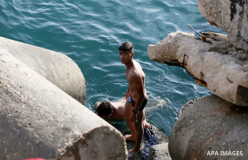 Palestinian youths swim as they enjoy in the Mediterranean Sea off the coast of Gaza City on May 5, 2017. Photo by Mohammed Asad