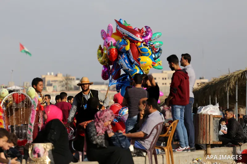 A Palestinian vendor sells ballons off the beach of Gaza City on May 5, 2017. Photo by Mohammed Asad