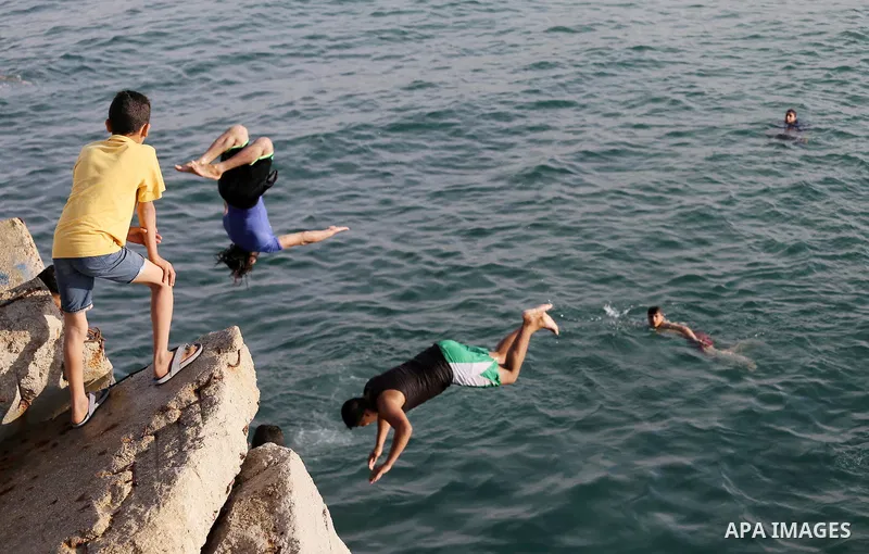 Palestinian youths jump into the Mediterranean Sea at the Gaza seaport in Gaza City on May 5, 2017. Photo by Mohammed Asad