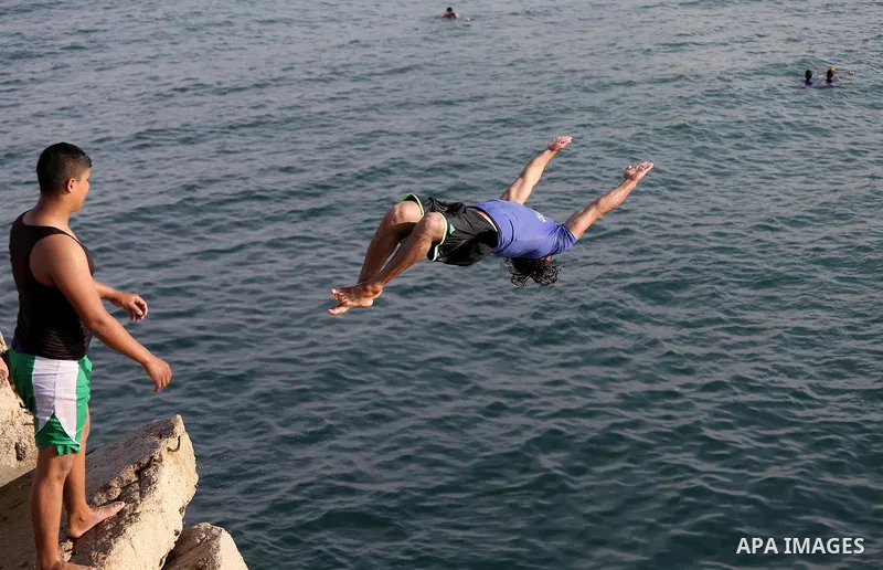 A Palestinian youth jumps into the Mediterranean Sea at the Gaza seaport in Gaza City on May 5, 2017. Photo by Mohammed Asad
