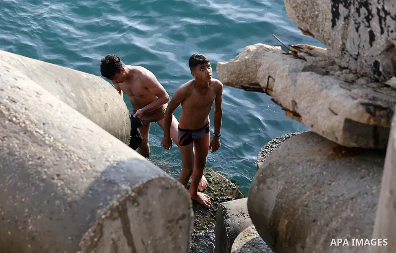 Palestinian youths swim as they enjoy in the Mediterranean Sea off the coast of Gaza City on May 5, 2017. Photo by Mohammed Asad