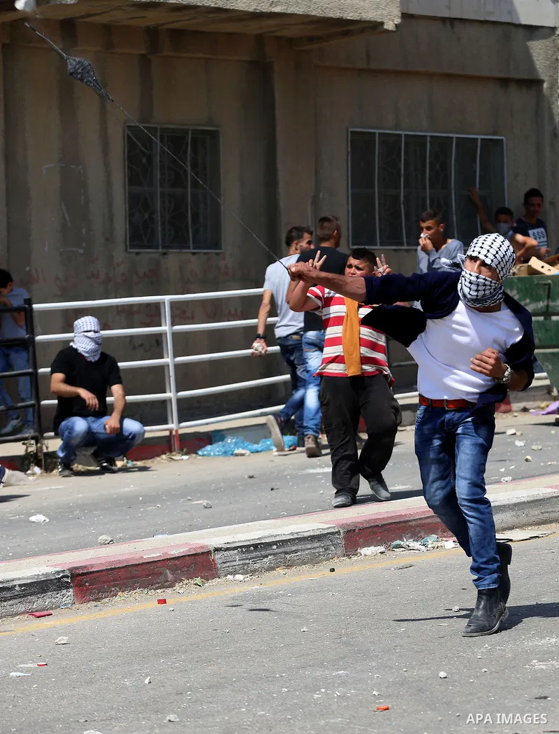 A Palestinian protester uses a slingshot to hurl stones towards Israeli security forces during clashes at a protest in support of Palestinian prisoners on hunger strike in Israeli jails, in the West Bank village of Beita...