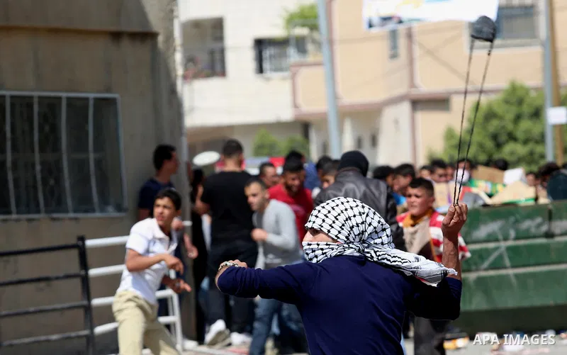 A Palestinian protester uses a slingshot to hurl stones towards Israeli security forces during clashes at a protest in support of Palestinian prisoners on hunger strike in Israeli jails, in the West Bank village of Beita...