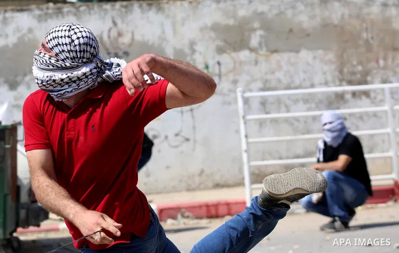 A Palestinian protester uses a slingshot to hurl stones towards Israeli security forces during clashes at a protest in support of Palestinian prisoners on hunger strike in Israeli jails, in the West Bank village of Beita...
