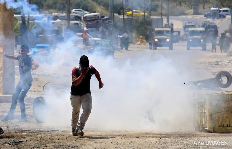 Palestinian protesters run for a cover from a tear gas canister fired by Israeli security forces during clashes at a protest in support of Palestinian prisoners on hunger strike in Israeli jails, in the West Bank village...