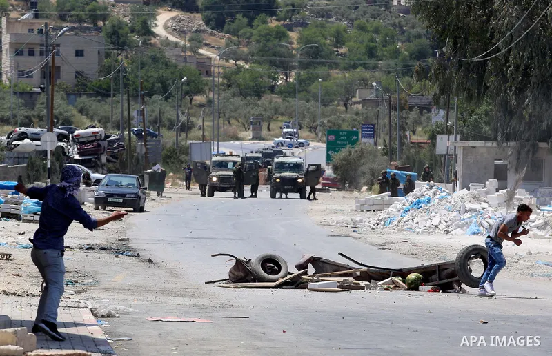 A Palestinian protester uses a slingshot to hurl stones towards Israeli security forces during clashes at a protest in support of Palestinian prisoners on hunger strike in Israeli jails, in the West Bank village of Beita...