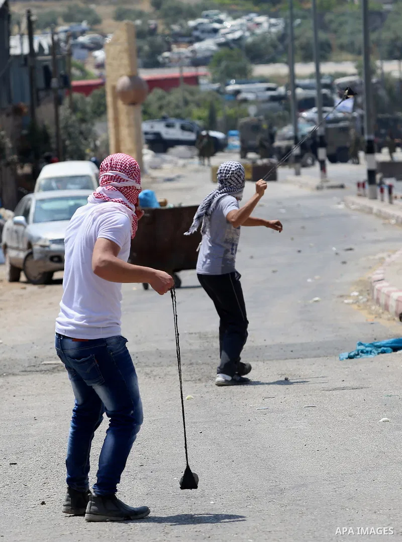 Palestinian protesters use a slingshot to hurl stones towards Israeli security forces during clashes at a protest in support of Palestinian prisoners on hunger strike in Israeli jails, in the West Bank village of Beita,...